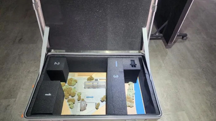 Custom Foam Protection Custom black foam insert inside open aluminum flight case with numbered die-cut compartments (1, 2, 3) precisely holding a detailed architectural scale model featuring miniature trees, bridge structure and landscape base – professional model protection
