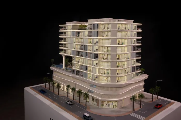 Maqueta a escala de un moderno edificio de apartamentos de lujo totalmente iluminado, con suelos interiores resplandecientes, amplios balcones, vegetación en la azotea, podio comercial curvo, calles bordeadas de palmeras y coches en miniatura sobre una base de exposición blanca: modelo arquitectónico de una vivienda residencial de primera calidad.
