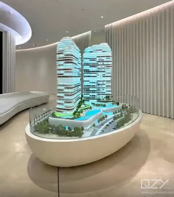 A completed high-rise scale model displayed in a building lobby post-completion, serving as a permanent exhibit of the development's design journey.